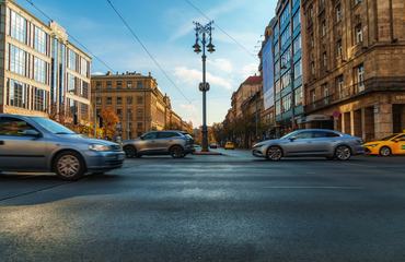 Budapest, Hungary - November 9, 2025: Motion blur of cars driving on a busy city street between historic buildings in Budapest Hungary during golden hour daylight.